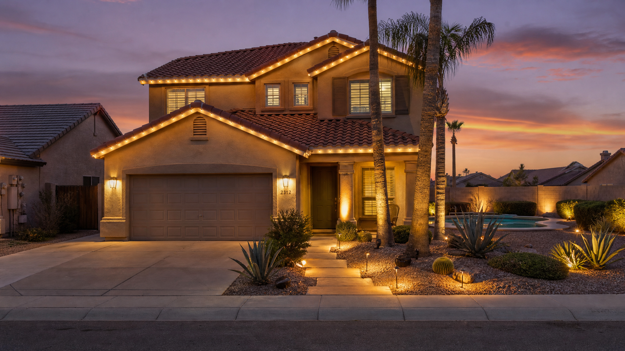 Phoenix suburban home with warm permanent roofline and landscape lighting at twilight, palm trees and desert xeriscape in the foreground