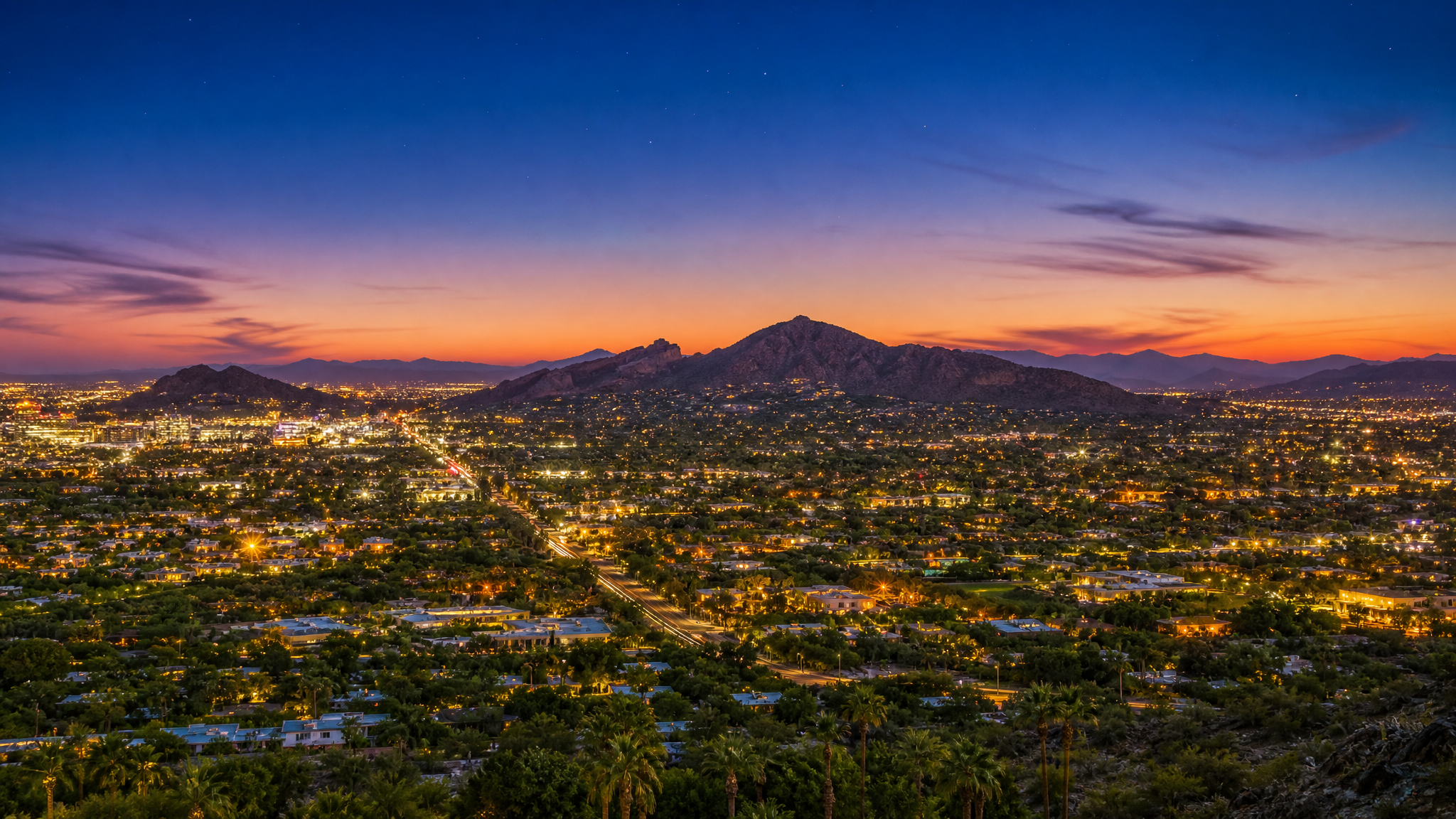 Aerial twilight view of the Phoenix and Scottsdale metro valley with city lights and desert mountains